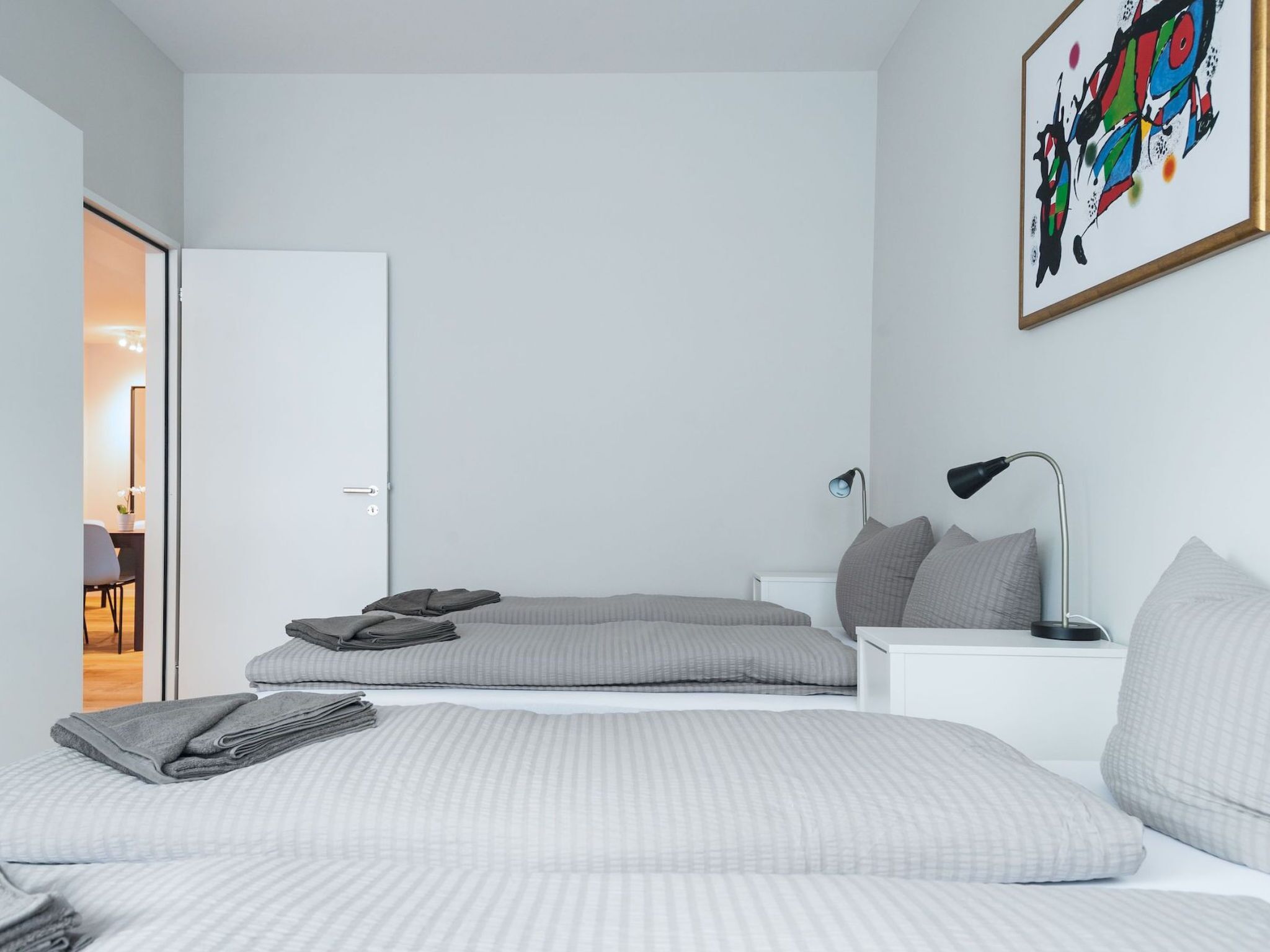 Una camera da letto moderna con un letto, comodini, una lampada e un quadro appeso al muro.