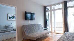 Une chambre moderne avec un canapé, un lit, une télévision et une grande fenêtre.