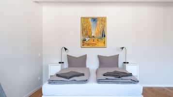 A modern bedroom with a white bed, two bedside lamps, and a painting on the wall.
