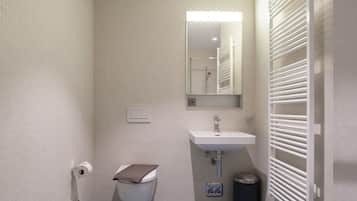 Pieni, moderni kylpyhuone, jossa on wc, pesuallas ja pyyhekoukku.