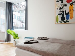 Ein Schlafzimmer mit einem Bett, einer Topfpflanze, einem blauen Sessel und einem Bild an der Wand.