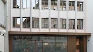 Een meerlaags gebouw met een modern architectonisch ontwerp, met een reeks rechthoekige ramen en een begane grond entree met glazen deuren.
