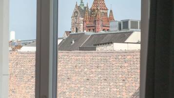 Blick auf ein Gebäude mit auffälligem roten und grünen Dach durch ein Fenster.