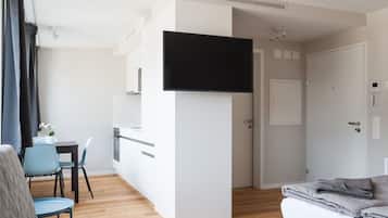 Ein modernes Hotelzimmer mit Flachbildfernseher, einer Küchenzeile, einem Essbereich und einem separaten Schlafbereich.