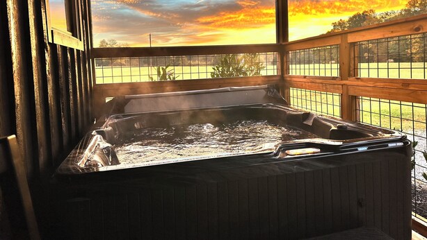 A hot tub under a wooden deck with a view of a sunset.