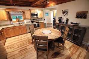 A kitchen with wooden cabinets, a round dining table, and a coffee station.