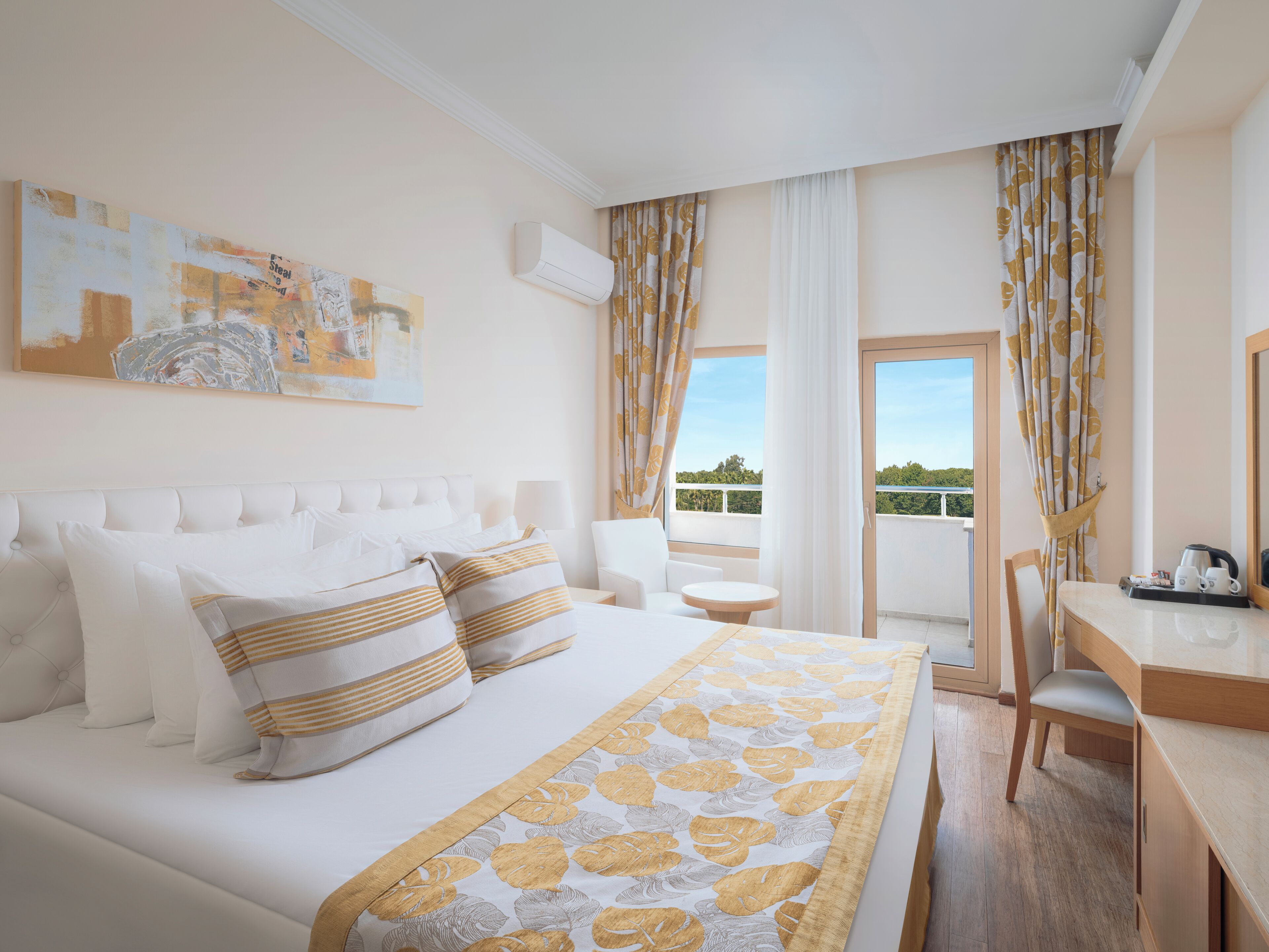 A hotel room with a bed, a desk, a chair, and a balcony with curtains.