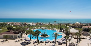 Un complexe hôtelier doté d’une grande piscine centrale, de chaises longues et offrant une vue sur la mer.
