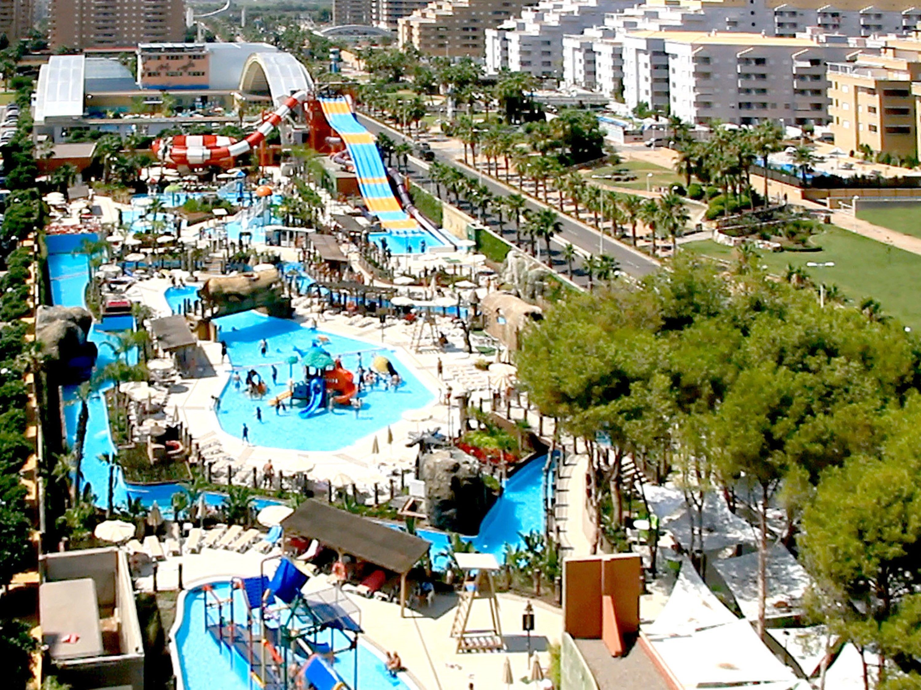 A resort with a large swimming pool, water slides, and a beach area.