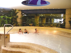 An indoor swimming pool with three people in the water, surrounded by plants and a decorative ceiling. - Magic Games (Oropesa del Mar)
