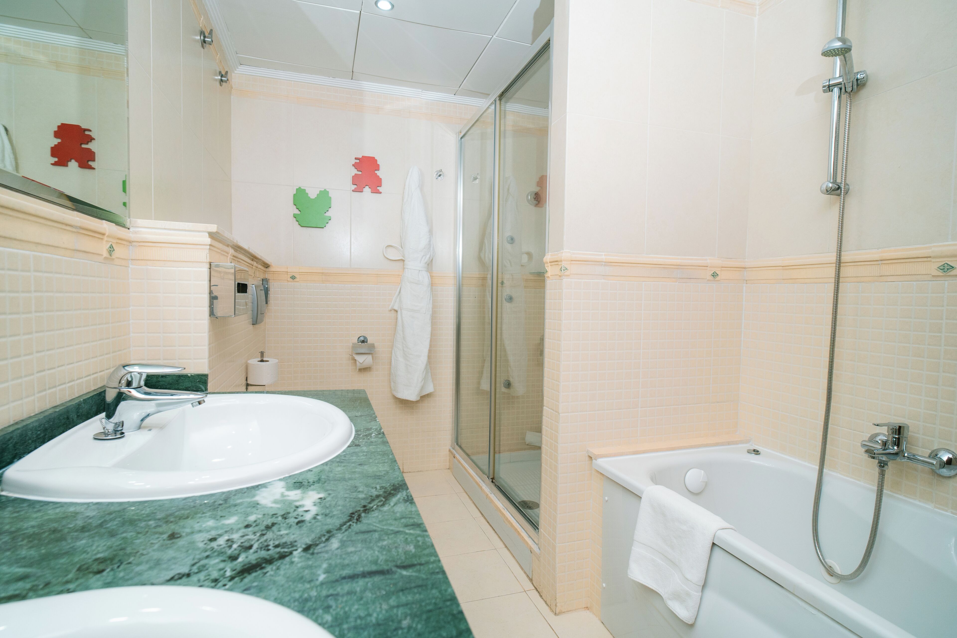 A bathroom with two sinks, a shower, and a glass-enclosed shower area.