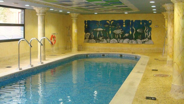Ein Innenpool mit Fliesen Decke, Wandgemälde und Rettungsboje.