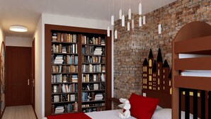 Ein Schlafzimmer mit Backsteinwand, einem großen Bücherregal, einem Bett mit roter Bettwäsche und einem weißen Stofftier.