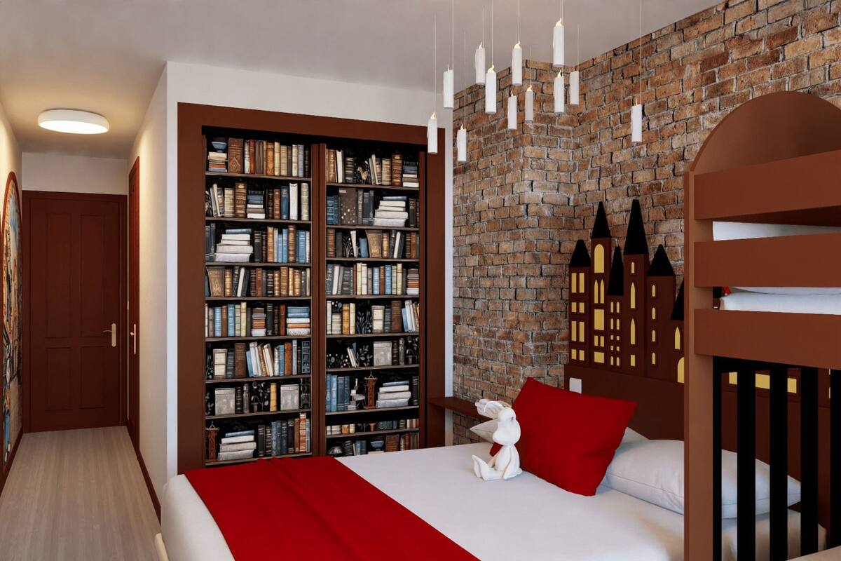 Une chambre avec un mur en briques, une grande bibliothèque, un lit avec une literie rouge et un jouet en peluche blanc.