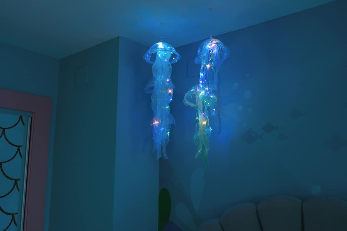 Deux sculptures de méduses illuminées dans une pièce aux nuances bleues.