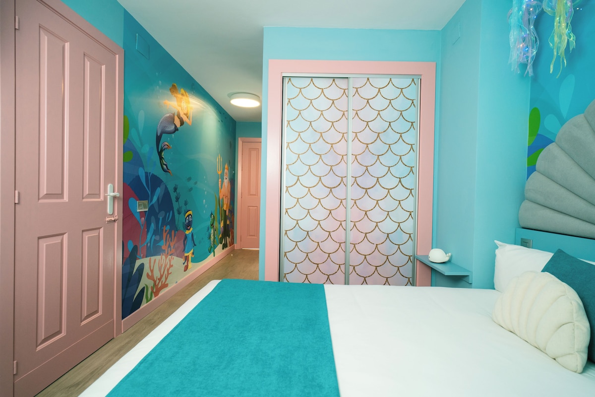 A bedroom with a bed, a nightstand, and a wall with a decorative pattern.