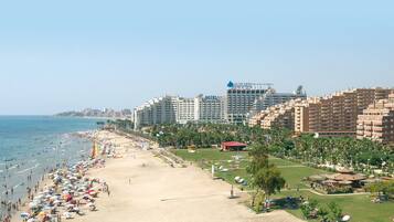Un resort en la playa con un hotel, varias construcciones y una vista despejada del océano.