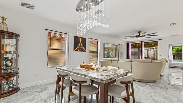 A modern dining area with a marble table, chairs, and a decorative ceiling light. - Family-Friendly 4BR Villa Near Disney - Kissimmee (Kissimmee)
