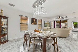 Een moderne eetruimte met een marmeren tafel, stoelen en een decoratieve plafondlamp.