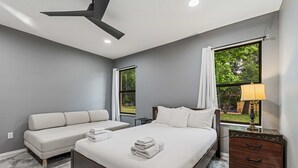 A hotel room with a bed, a sofa, a nightstand, and two windows. - Family-Friendly 4BR Villa Near Disney - Kissimmee (Kissimmee)