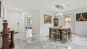 A spacious dining area with a marble floor, a chandelier, and a painting of the Eiffel Tower. - Family-Friendly 4BR Villa Near Disney - Kissimmee (Kissimmee)