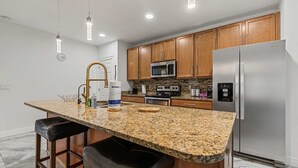 A kitchen with granite countertops, wooden cabinets, stainless steel appliances, and pendant lighting. - Family-Friendly 4BR Villa Near Disney - Kissimmee (Kissimmee)