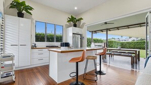 Een moderne keuken met een centraal eiland, barkrukken en uitzicht op de omgeving.