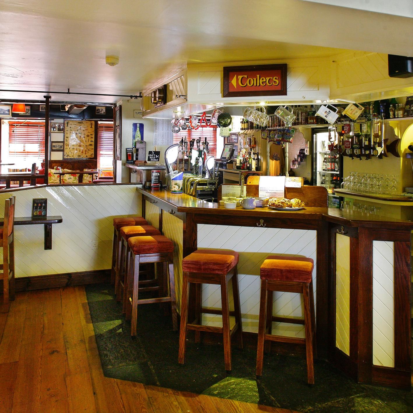 A bar with stools, a counter, and a sign that reads 'Coles.'