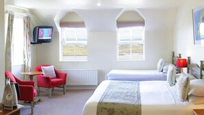 Habitación de hotel con dos camas, televisión, una silla roja y vistas al campo.