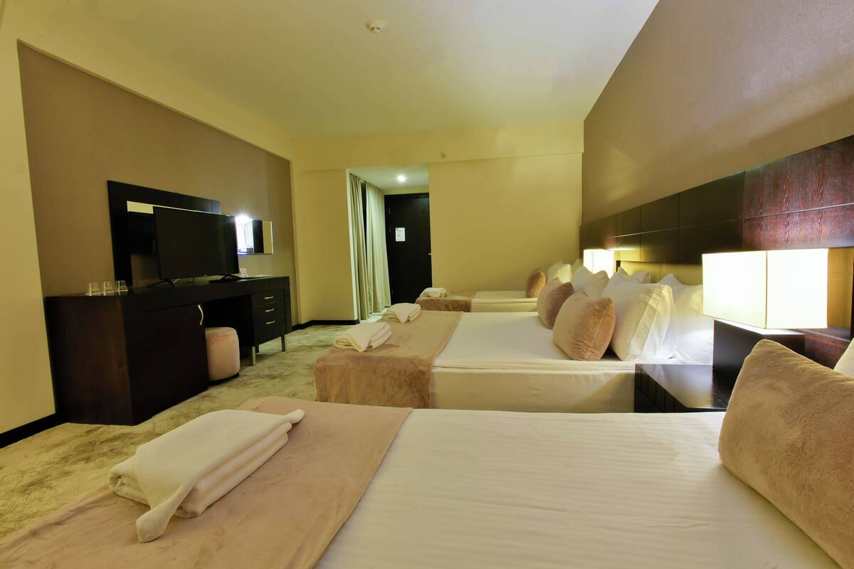 Ein Hotelzimmer mit zwei Betten, einem Schreibtisch, einem Fernseher und einem durch eine geöffnete Tür einsehbaren Badezimmer.