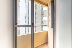 A balcony with a glass door, a red railing, and a view of a modern building. - Br156 54 - Sirio Libanes (São Paulo)