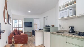 Ett kompakt bostadsutrymme med ett litet kök, en matplats och en sittgrupp med en soffa och ett bord.