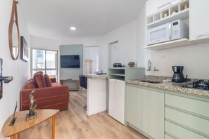 A compact living space with a kitchenette, a dining area, and a seating area with a sofa and a table. - Br156 54 - Sirio Libanes (São Paulo)