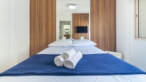 Una habitación de hotel con una cama, una manta azul y dos toallas enrolladas.