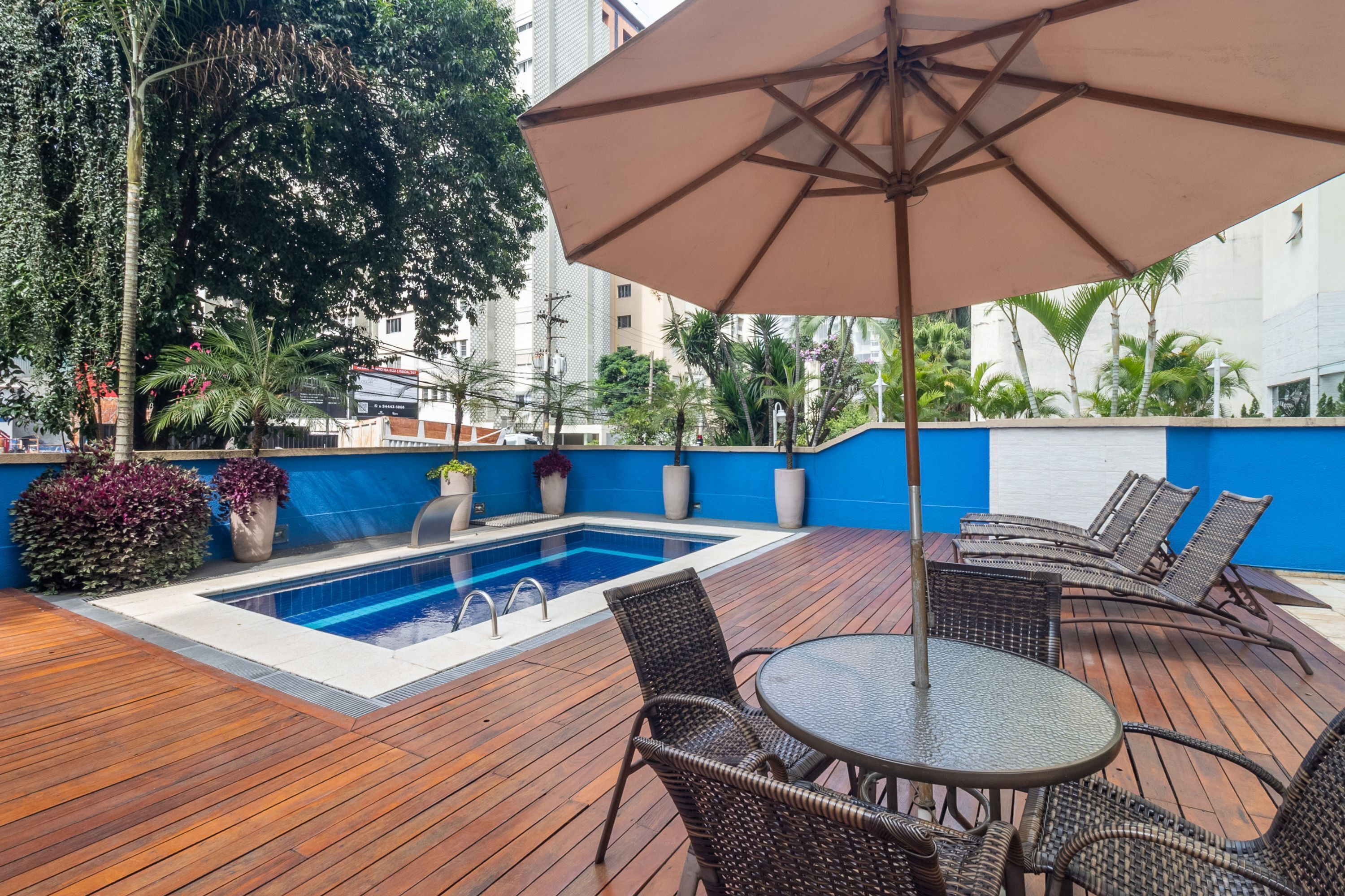 Zona de piscina en la azotea con piscina azul, sillas de descanso y una sombrilla.