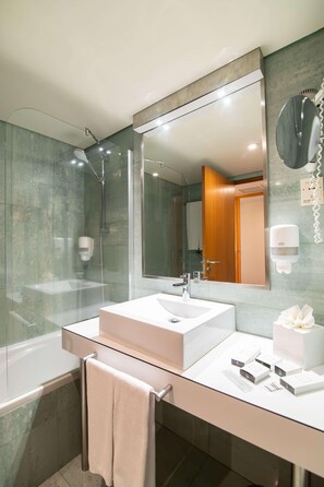 Ein modernes Badezimmer mit einer gläsernen Duschkabine, einem großen Spiegel und einem weißen Waschbecken.