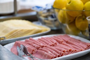 Un bufé con jamón en rodajas y un tazón de limones.