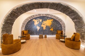 Un vestíbulo con un arco de piedra, un mural de un mapa mundial y muebles modernos.