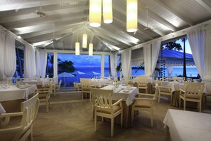 A restaurant with multiple tables and chairs, large windows with curtains, and hanging light fixtures. - Bahia Principe Escape Samaná Hyatt Incl Co Adult O (Samaná)