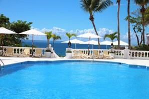 A pool with lounge chairs and umbrellas, palm trees, and a view of the ocean. - Bahia Principe Escape Samaná Hyatt Incl Co Adult O (Samaná)