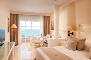 A hotel room with a bed, a desk, a chair, and a view of the sea. - Bahia Principe Escape Samaná Hyatt Incl Co Adult O (Samaná)