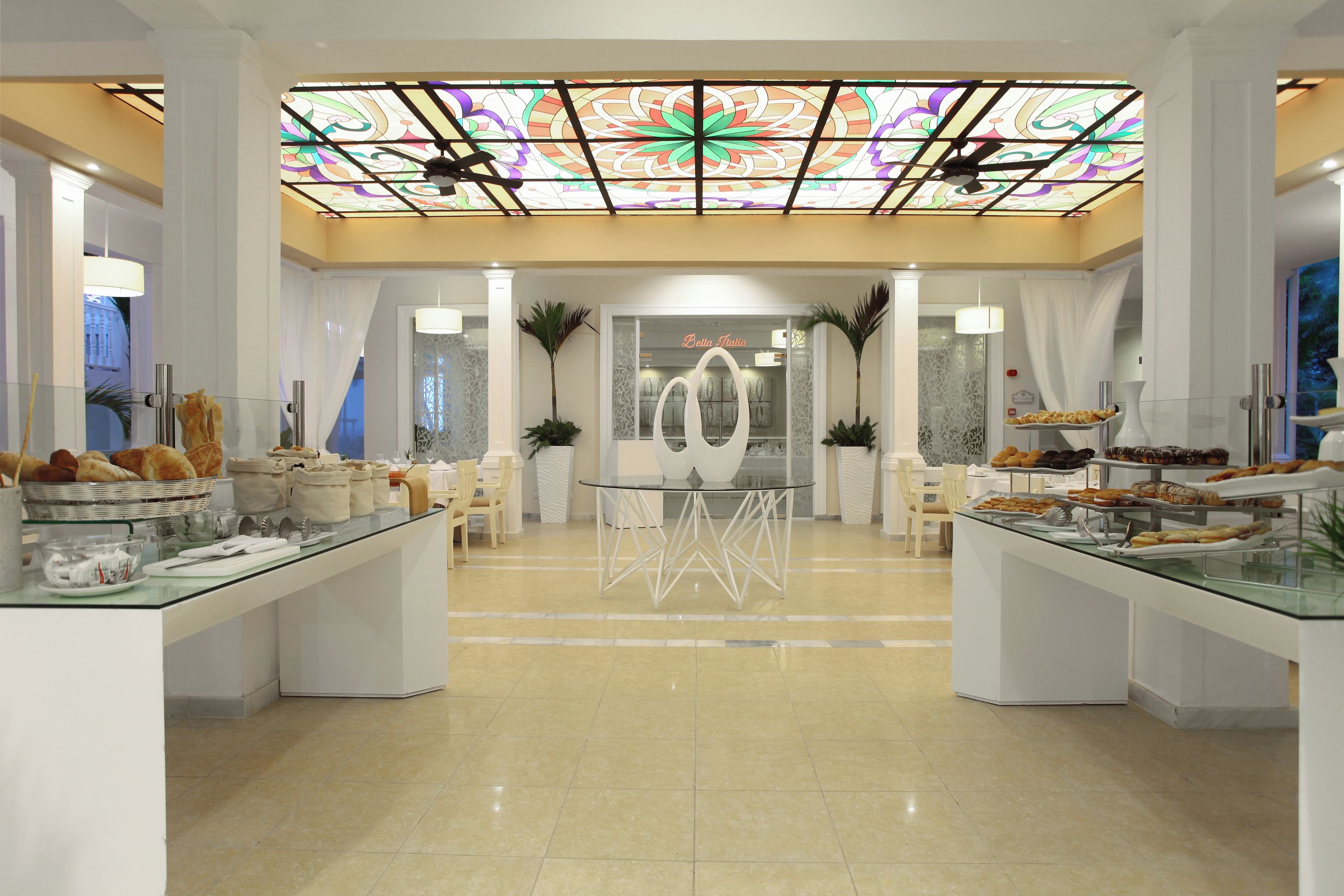 Un hall d’hôtel doté d’un bar à café avec un comptoir en verre, d’un bureau d’accueil et d’un plafond décoratif.