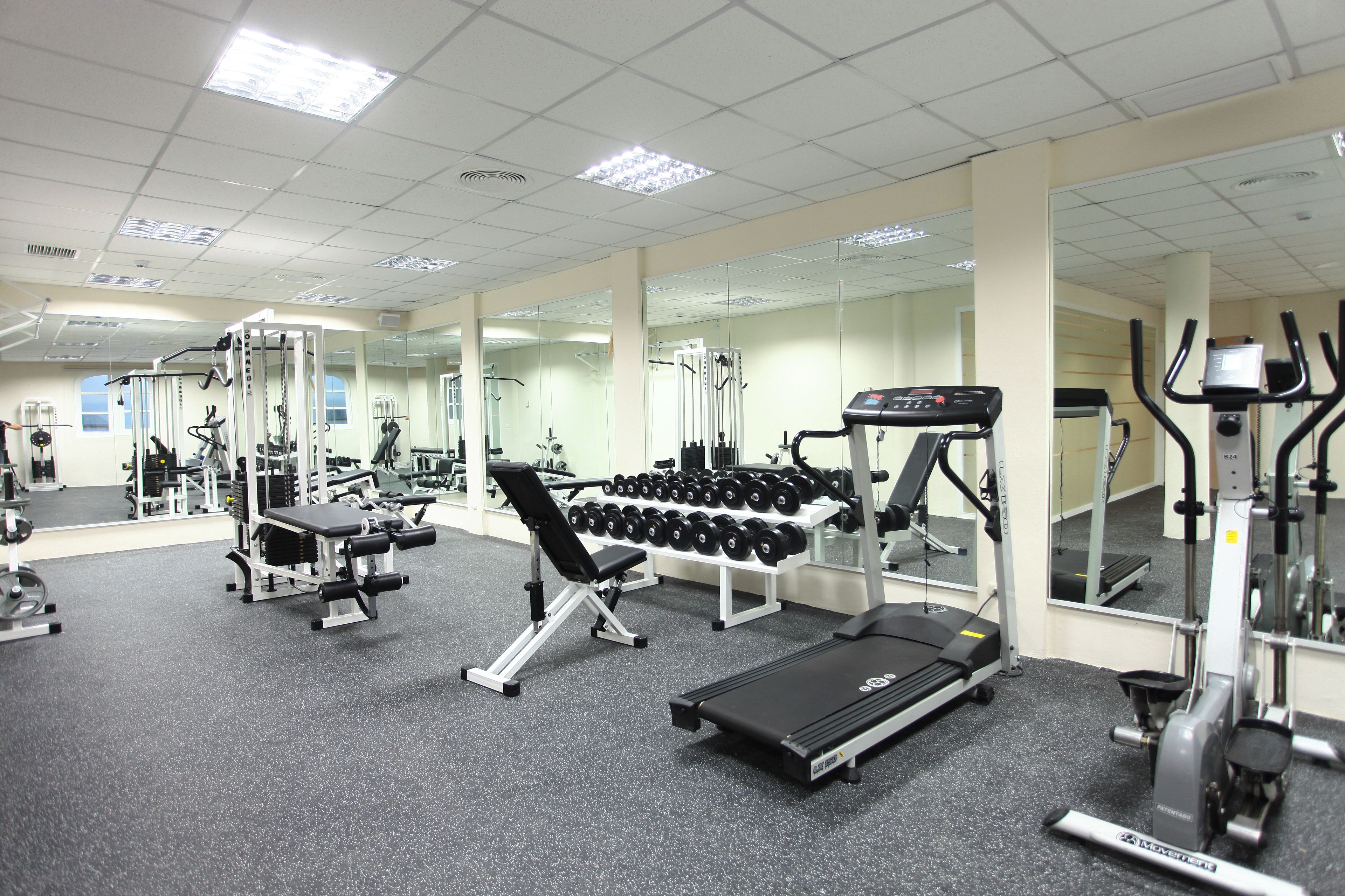 A gym with exercise equipment, mirrors, and a treadmill.