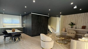 Ein modernes Wohnzimmer mit Essbereich, einer Treppe und einer Küche.