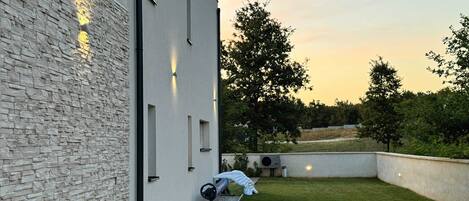 Un edificio moderno con fachada de piedra, techo plano y un patio cubierto de césped.