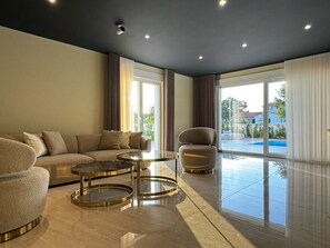 A modern living room with a sofa, two round tables, and a chair. - Villa Nobel (Istria - Svetvinčenat) (Svetvinčenat)