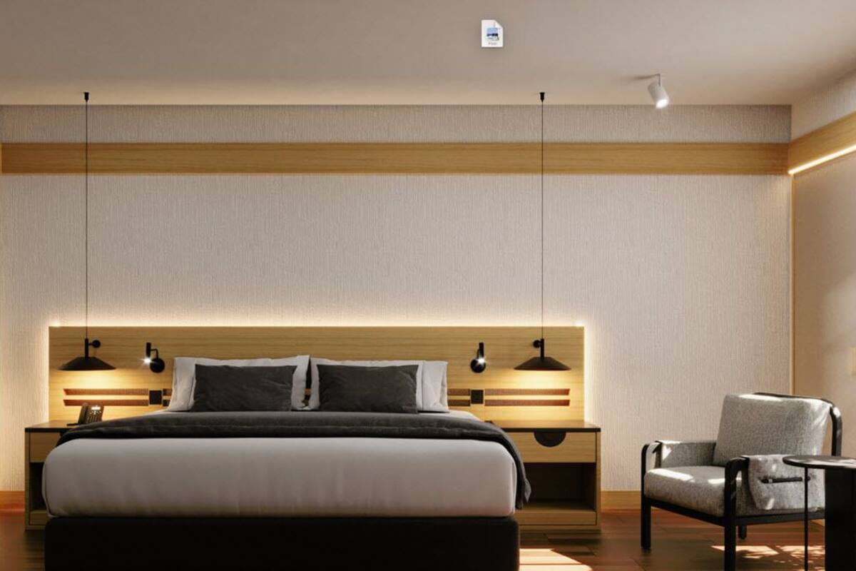 A modern hotel room with a large bed, bedside lamps, a chair, and a large window.