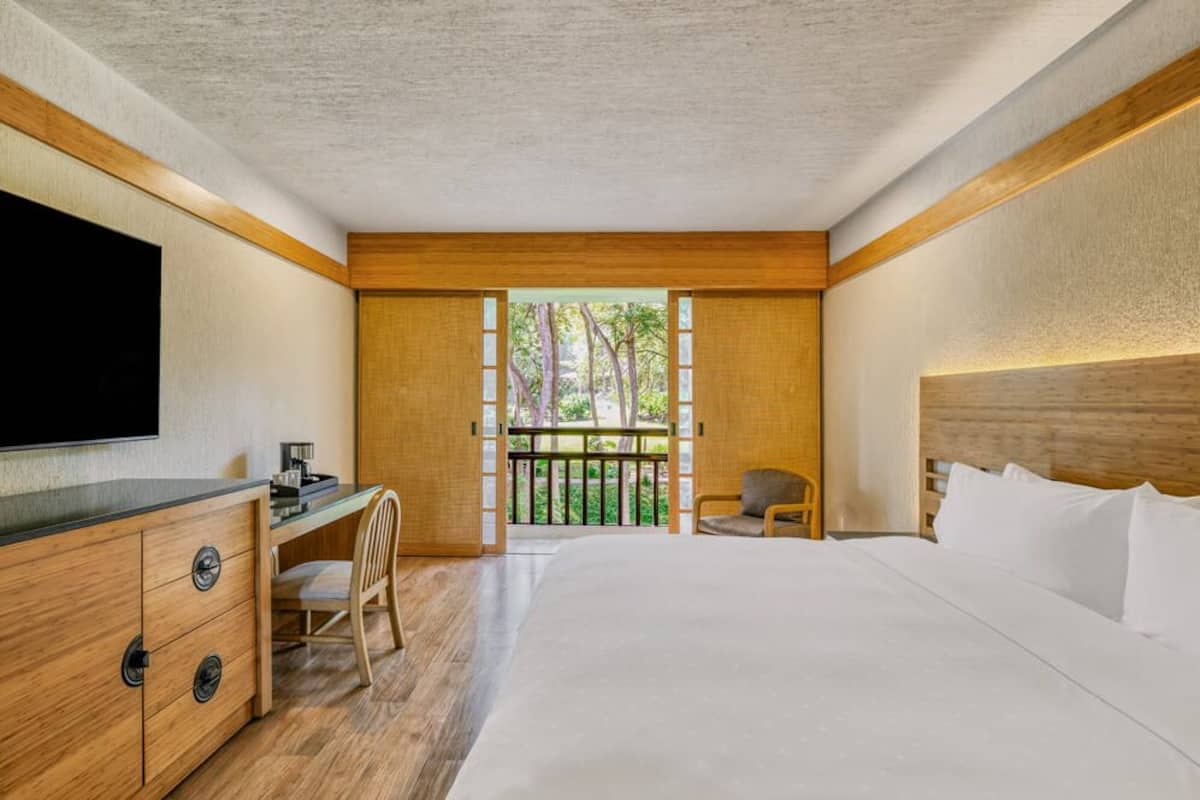 A bedroom with a bed, a desk, a chair, and a TV.