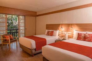Une chambre d’hôtel avec deux lits, une tête de lit en bois, une chaise, un balcon avec des portes vitrées et un téléphone sur la table de chevet.