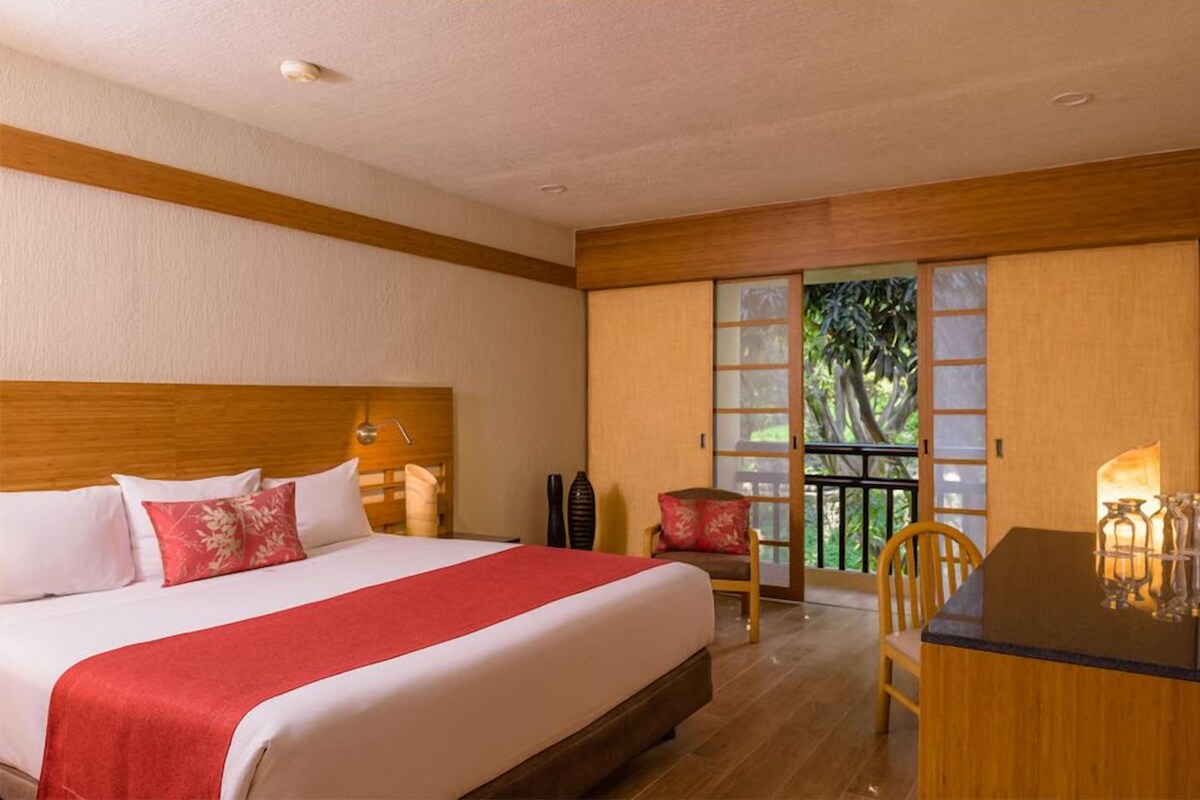 Une chambre d’hôtel équipée d’un lit, d’un bureau, d’une chaise, d’une fenêtre avec vue et d’une porte coulissante.